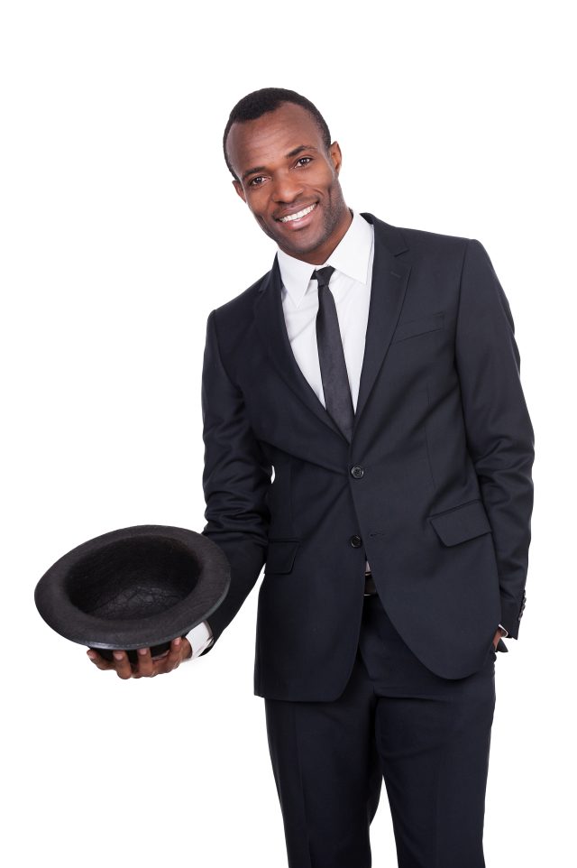 Confident and charming. Handsome young African man in full suit holding a hat in his hand and smiling while standing isolated on white background